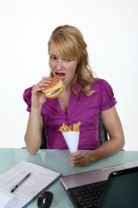 woman eating junk food at desk